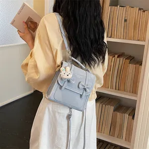 Dettaglio di una borsa a tracolla stile preppy azzurra con un simpatico ciondolo a coniglio