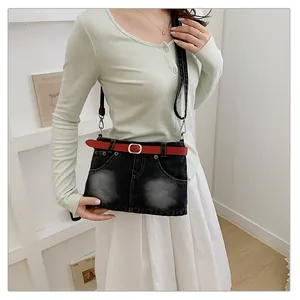 Close-up of a stylish denim crossbody bag with a red belt detail worn by a model