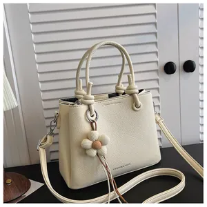 Vista detallada del bolso cubo de cuero granulado crema con charm de flor