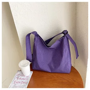 Large capacity purple checkered nylon crossbody bag displayed on a wooden table with lifestyle props