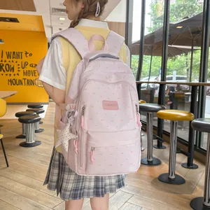 Detailweergave van roze schoolrugzak met hartjespatroon en ster-accessoire charm