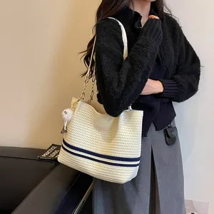 Detailed view of striped woven tote bag carried by a model in a stylish outfit