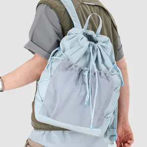 Back view of a light blue fashionable drawstring backpack with a mesh front pocket.