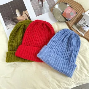 Close-up of three thick ribbed knitted beanies in green, red, and blue colors