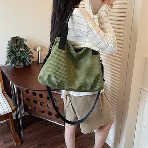Grande borsa tote a scacchi verdi indossata da una persona in un ambiente accogliente