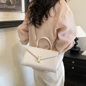 Elegant white envelope-style handbag styled with a peach blouse for a professional look