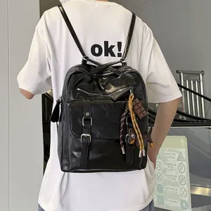 Back view of a black large capacity leather commuter backpack with charms on a model