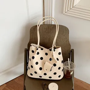 Vintage cream tote bag with black polka dots and matching pouch on a wooden chair