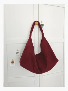 Vintage burgundy suede large capacity tote bag hanging on a minimalist white door