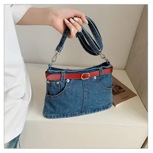 Unique denim shoulder bag with jean pocket design and decorative red belt detail.