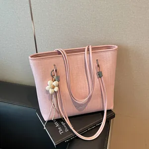 Close-up of a pink textured tote bag with a stylish white floral charm accessory.