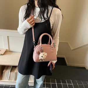 Close-up of a pink Boston handbag featuring a plush bear charm worn by a model