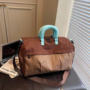 Detail of a brown travel duffle bag with mint green padded handles in a lifestyle setting