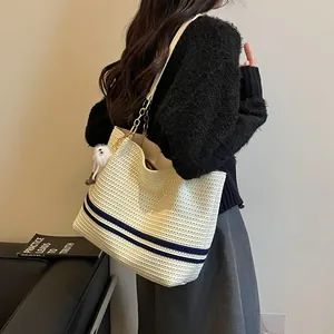 Detailed side view of a stylish woven tote bag with navy stripes worn by a model