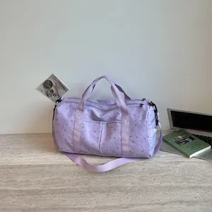Detalle de bolsa de viaje morada con diseño de estrellas y lunas en escritorio