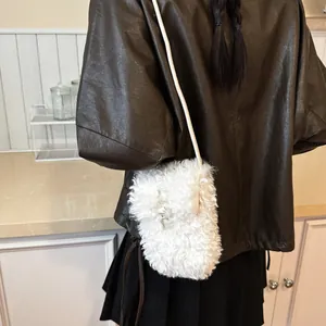Detail view of a white fuzzy crossbody phone bag styled with a brown leather jacket