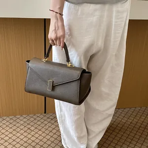 Detail of a stylish dark taupe handbag with elegant gold hardware for a chic summer look