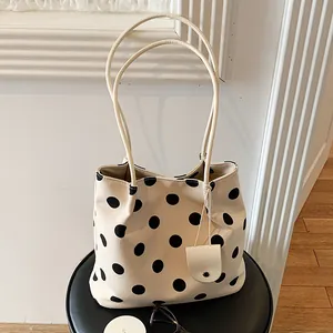 Elegant cream-colored tote bag featuring black polka dots and slim shoulder straps