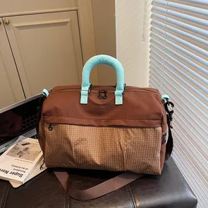 Brown travel duffel bag with light blue handles on a leather bench setting
