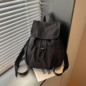 Close-up of a stylish black drawstring pleated backpack with flap and side pockets.