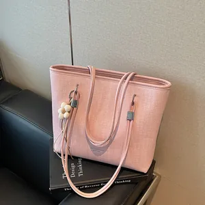 Close-up of a pink textured large capacity tote bag featuring elegant double handles.