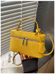 Detail view of a stylish yellow vanity box bag featuring a silver zipper and textured finish.