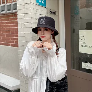 Detailed view of a black cotton bucket hat with cute embroidered white bunny ears on front