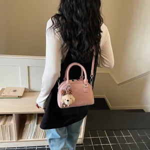 Pink Boston handbag with poodle charm shown on model's shoulder in interior