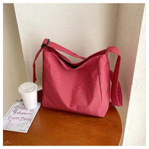 Close-up detail of a red checkered nylon hobo shoulder bag for women on a wooden table