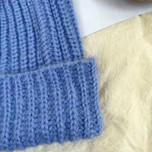 Close-up of light blue thick knit wool beanie with ribbed texture and soft feel.