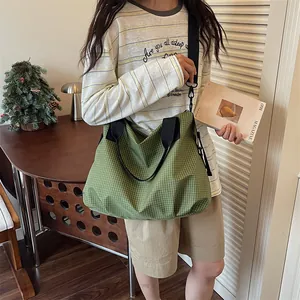 Dettaglio di una borsa tote a scacchi verdi di grande capacità indossata da una modella.