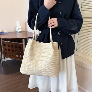 Detailed view of cream woven tote bag with elegant texture and slim straps