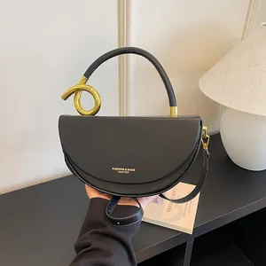 Nahaufnahme einer schwarzen Satteltasche aus Leder mit goldenem Ringgriff und Textur