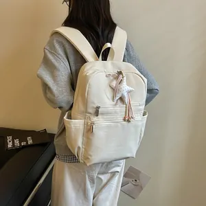 Vista detallada de una mochila ligera de estilo coreano en blanco crema con dije de estrella.