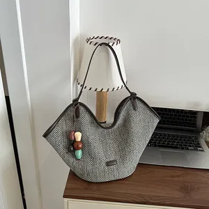 Detail view of a handmade woven straw tote bag featuring a colorful bead charm on a desk