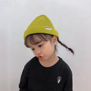Close-up detail of a young child wearing a vibrant lime green ribbed knitted beanie hat