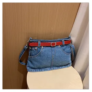 Detailed view of niche denim skirt style shoulder bag with vibrant red belt accent
