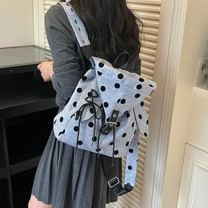 Detailed back view of a stylish light blue polka dot backpack worn by a female student in grey
