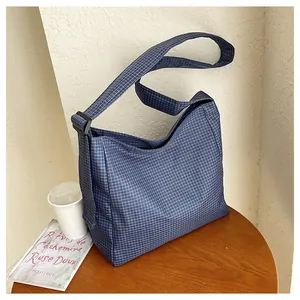 Close-up of blue checkered nylon crossbody bag on a wooden table with lifestyle props