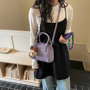 Close-up view of a stylish purple Boston handbag with a cute dog plush charm accessory