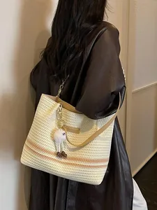 Stylish summer woven tote bag with orange stripes and white fuzzy charm accessory