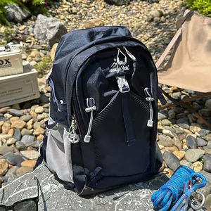 Dark blue waterproof hiking backpack placed on river stones for outdoor travel adventure