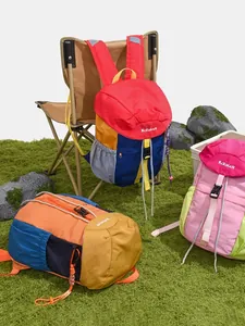 Vibrant multi-color outdoor backpacks displayed on grass with camping chair scene.
