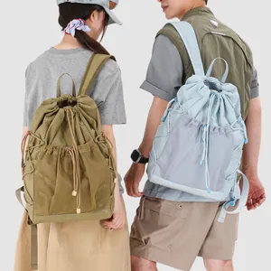 Back view of models wearing drawstring backpacks with mesh pockets and grid pattern