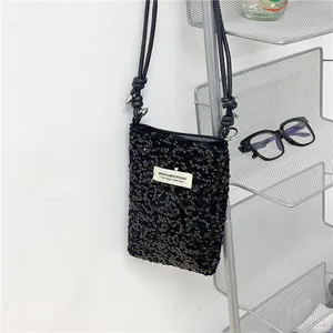 Dettaglio di una borsa a tracolla nera con paillettes alla moda con toppa bianca