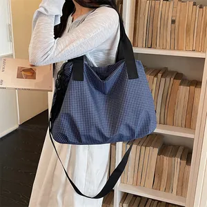 Borsa da viaggio grande a scacchi blu e bianchi mostrata sul modello nel quotidiano