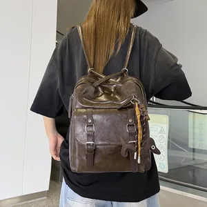 Stylish large capacity brown faux leather commuter backpack worn by a model in a city.