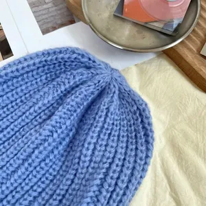 Close-up view of a blue chunky knit beanie showing detailed ribbed texture and stitching.