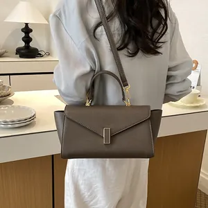 Detail of dark brown leather handbag with gold clasp and detachable shoulder strap