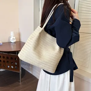 Side detail view of a cream woven tote bag styled with a navy blouse for a chic look.
